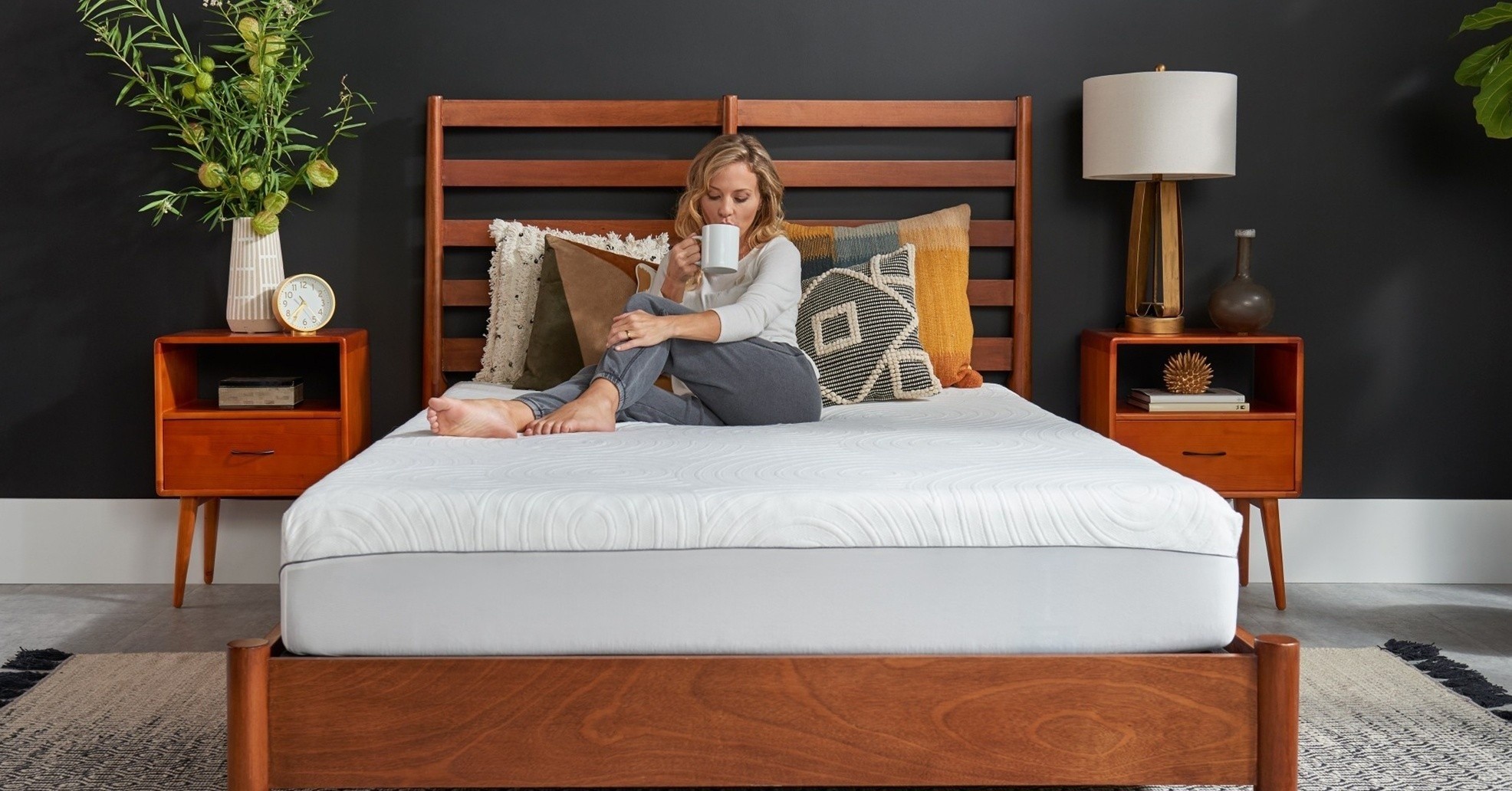 a woman sitting on a mattress with the TEMPUR-Protect Mattress Protector on over